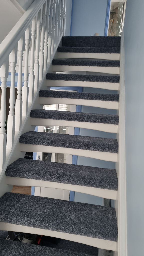 Stair carpet fitter on stairs in a home in Swanage.